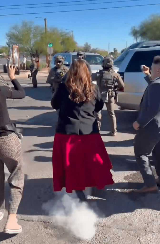 A smoke plume erupts underneath Rep. Adelita Grijalva after a federal agent fired a pellet at her for advancing too close during an ICE raid in Tucson, Arizona.